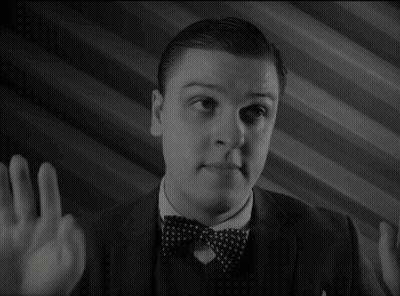A Man In A Suit And Bow Tie Is Pointing GIF