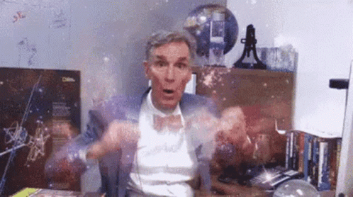 A Man In A Suit And Bow Tie Is Sitting At A Desk In Front Of A Computer . GIF