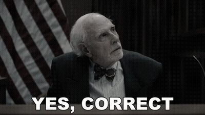 A Man In A Suit And Bow Tie Is Sitting In Front Of A Sign That Says Yes Correct GIF