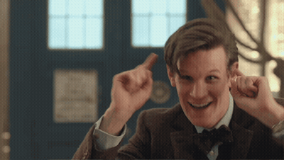 A Man In A Suit And Bow Tie Is Smiling And Holding Something In His Hand GIF