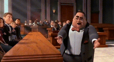 A Man In A Suit And Bow Tie Is Standing In Front Of A Group Of People . GIF