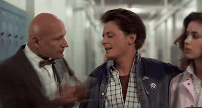 A Man In A Suit And Bow Tie Is Talking To A Man In A Plaid Shirt And A Girl In A Pink Jacket . GIF