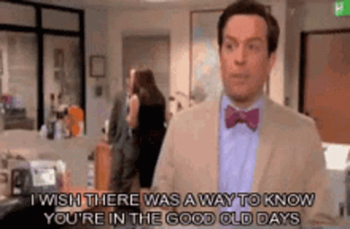 A Man In A Suit And Bow Tie Is Talking To Someone In An Office . GIF