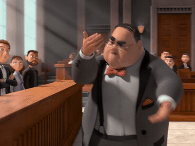 A Man In A Suit And Bow Tie Stands In Front Of A Jury GIF