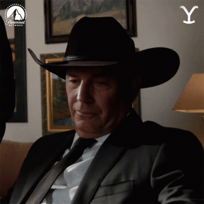 A Man In A Suit And Cowboy Hat Is Sitting In Front Of A Paramount Network Sign GIF