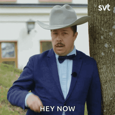 A Man In A Suit And Cowboy Hat Is Standing Next To A Tree And Says Hey Now GIF