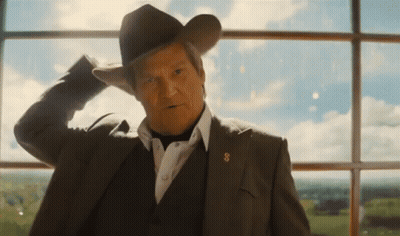A Man In A Suit And Cowboy Hat Stands In Front Of A Window With His Hand On His Head GIF