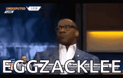 A Man In A Suit And Glasses Says Eggzacklee On A Television Show . GIF