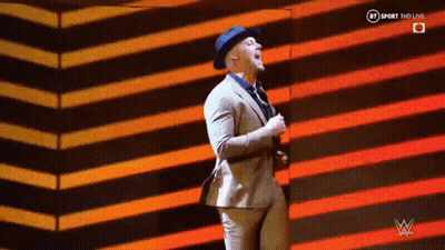 A Man In A Suit And Hat Is Dancing On A Stage In Front Of A Striped Background . GIF