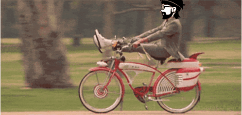 A Man In A Suit And Hat Is Riding A Red And White Bicycle GIF