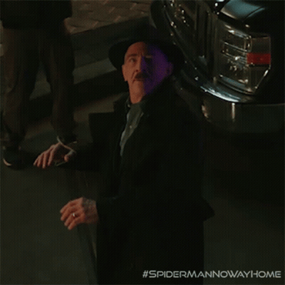 A Man In A Suit And Hat Is Standing In Front Of A Purple Car With The Hashtag #Spidermannowawayhome GIF