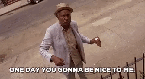 A Man In A Suit And Hat Is Standing On A Sidewalk Holding A Can Of Soda And Talking To Someone . GIF