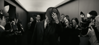 A Man In A Suit And Hat Is Surrounded By People Taking Pictures GIF