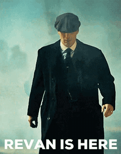 A Man In A Suit And Hat Is Walking In Front Of A Sign That Says ' Revan Is Here ' . GIF