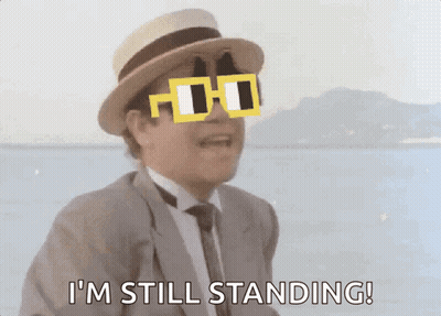 A Man In A Suit And Hat Is Wearing Sunglasses And Says I 'M Still Standing GIF