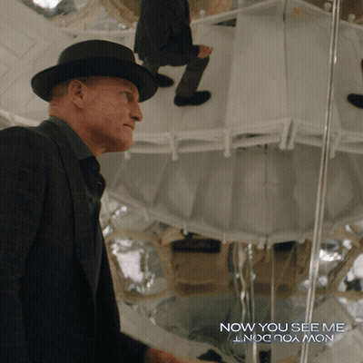 A Man In A Suit And Hat Stands In Front Of A Mirror With The Words Now You See Me GIF