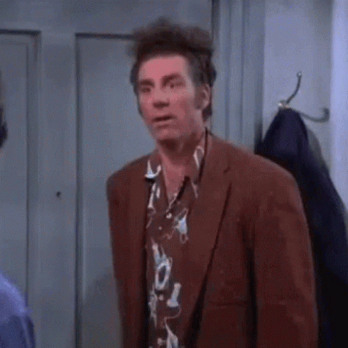 A Man In A Suit And Hawaiian Shirt Is Standing In A Room . GIF