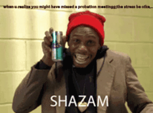 A Man In A Suit And Red Hat Holds A Can Of Shazam GIF