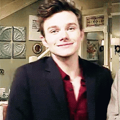 A Man In A Suit And Red Shirt Is Standing In A Living Room . GIF