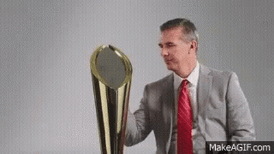A Man In A Suit And Red Tie Is Holding A Large Trophy . GIF