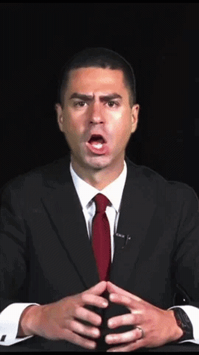 A Man In A Suit And Red Tie Is Making A Surprised Face GIF