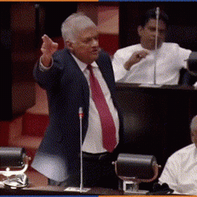 A Man In A Suit And Red Tie Is Speaking Into A Microphone GIF