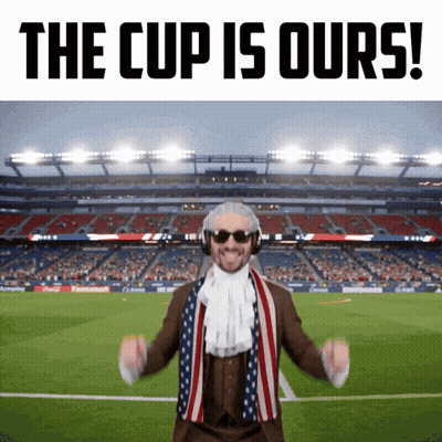 A Man In A Suit And Scarf Stands In Front Of A Soccer Stadium With The Words The Cup Is Ours GIF
