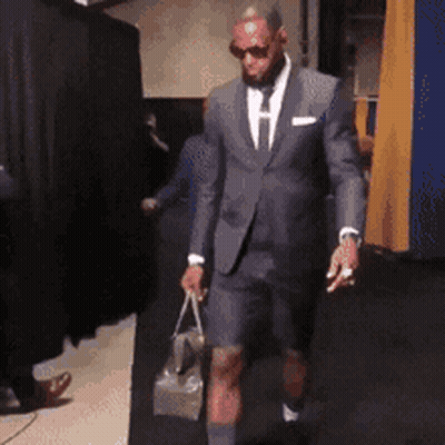 A Man In A Suit And Shorts Holds A Bag GIF