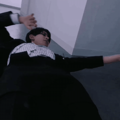 A Man In A Suit And Striped Shirt Is Laying On The Floor With His Arms Outstretched GIF