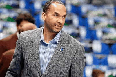 A Man In A Suit And Striped Shirt Is Standing In Front Of A Crowd . GIF