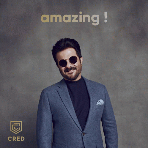 A Man In A Suit And Sunglasses Gives A Thumbs Up In Front Of An Amazing Sign GIF
