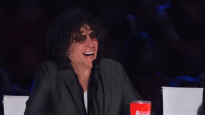 A Man In A Suit And Sunglasses Is Laughing While Sitting At A Table . GIF