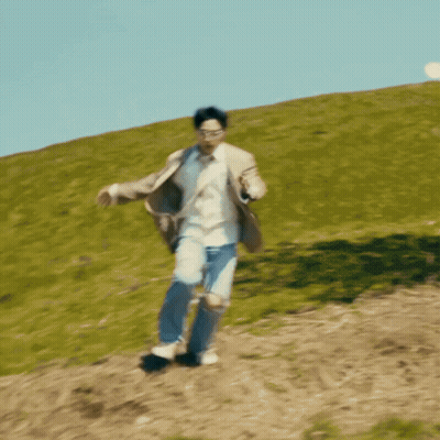 A Man In A Suit And Sunglasses Is Running Down A Hill GIF