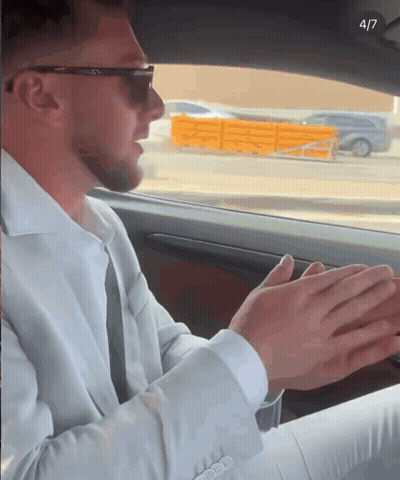 A Man In A Suit And Sunglasses Is Sitting In A Car With His Hands Folded In Front Of Him GIF