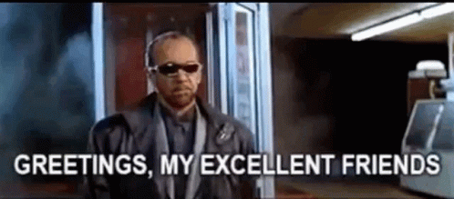 A Man In A Suit And Sunglasses Is Standing In Front Of A Window And Says `` Greetings , My Excellent Friends '' . GIF