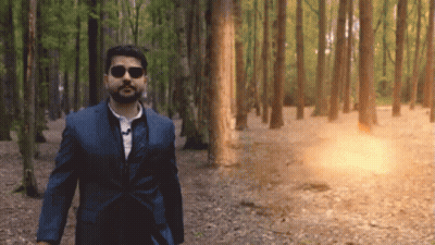 A Man In A Suit And Sunglasses Walks Through The Woods GIF