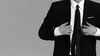 A Man In A Suit And Tie Adjusts His Tie GIF