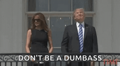 A Man In A Suit And Tie And A Woman In A Black Dress Are Standing On A Balcony . GIF