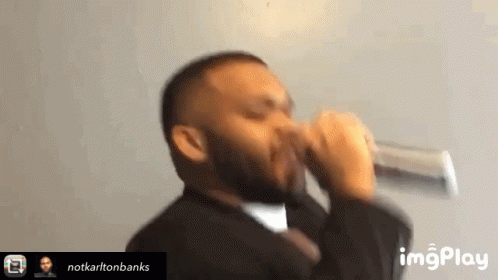 A Man In A Suit And Tie Drinking From A Glass . GIF