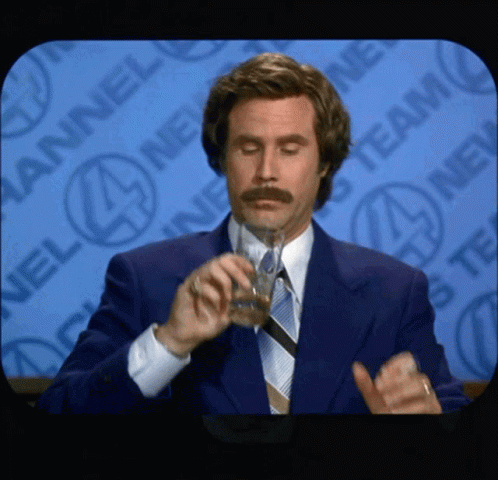 A Man In A Suit And Tie Drinks From A Glass GIF