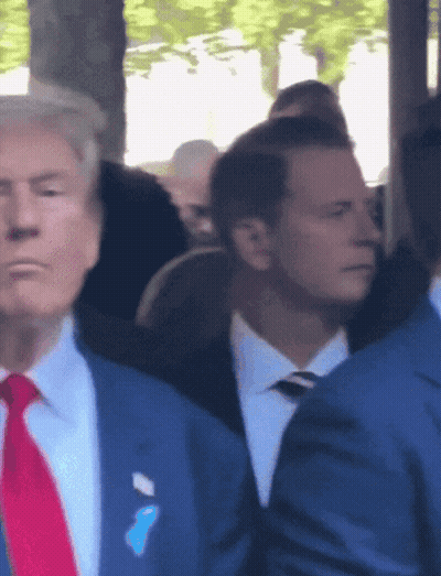 A Man In A Suit And Tie Has A Blue Ribbon On His Pocket GIF