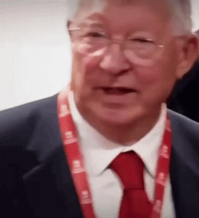 A Man In A Suit And Tie Has A Lanyard Around His Neck That Says ' Lg ' GIF