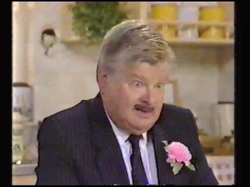 A Man In A Suit And Tie Has A Pink Flower In His Lapel . GIF