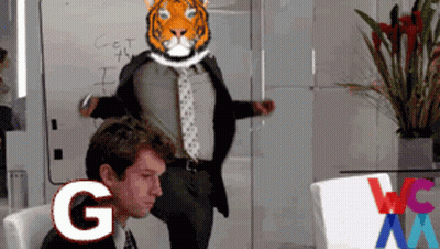 A Man In A Suit And Tie Has A Tiger Head On His Head And The Letter G Is Next To Him GIF