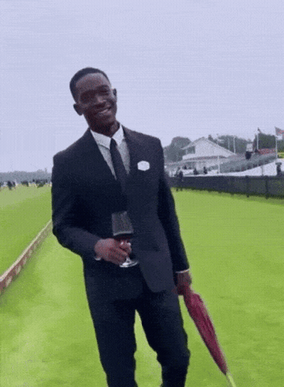 A Man In A Suit And Tie Holding A Glass Of Wine And An Umbrella GIF