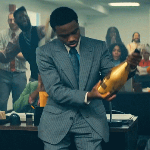 A Man In A Suit And Tie Holds A Bottle Of Champagne GIF