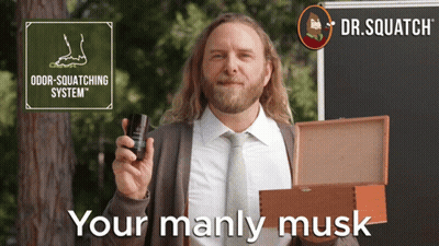 A Man In A Suit And Tie Holds A Bottle Of Odor-Squatching System In His Hand GIF