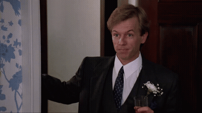 A Man In A Suit And Tie Holds A Glass In His Hand GIF