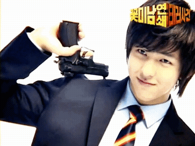 A Man In A Suit And Tie Holds A Gun In Front Of His Head GIF