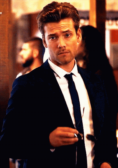 A Man In A Suit And Tie Holds A Pair Of Sunglasses In His Hand GIF